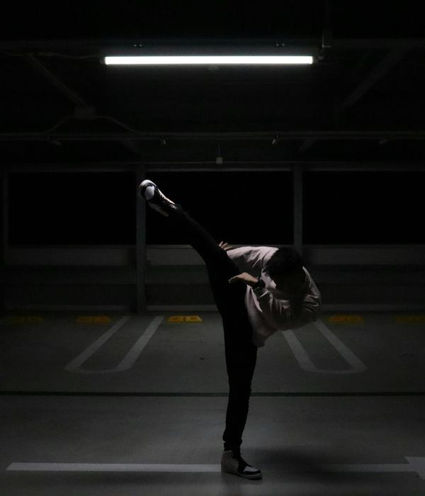 Man performing a controlled strength exercise in a minimalist dark environment.